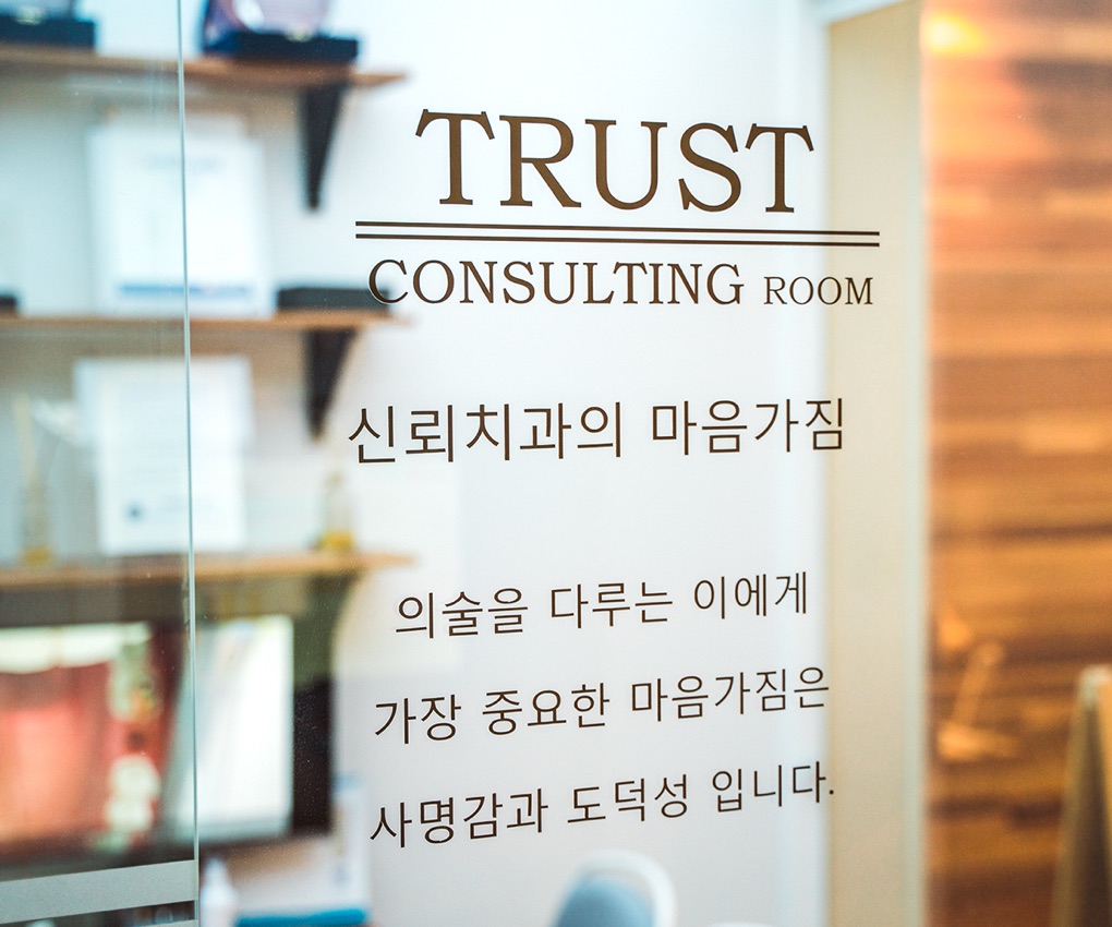 「신뢰치과의 마음가짐 — 의술을 다루는 이에게 가장 중요한 마음가짐은 사명감과 도덕성입니다」가 적힌 상담실 유리문